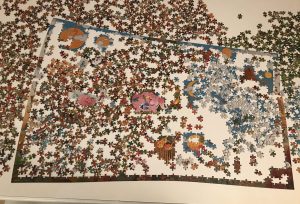 Person assembling colorful jigsaw puzzle pieces on table with timer